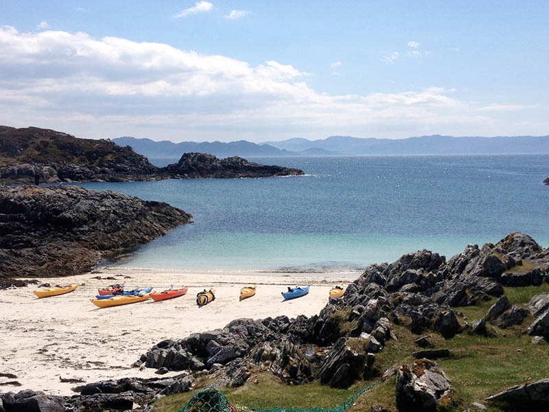 Responsible tourism - kayaks waiting by a beach. 