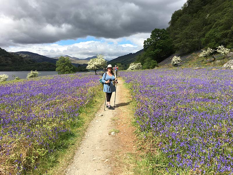 a woman posing next to bluebells next to loch lomond