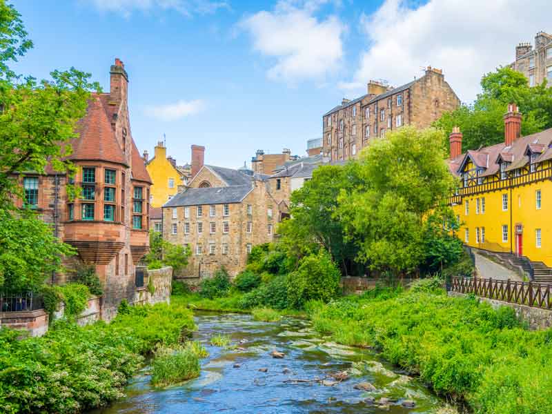 Quaint Dean Village in Edinburgh with historic, colourful stone buildings and a peaceful riverside walkway.