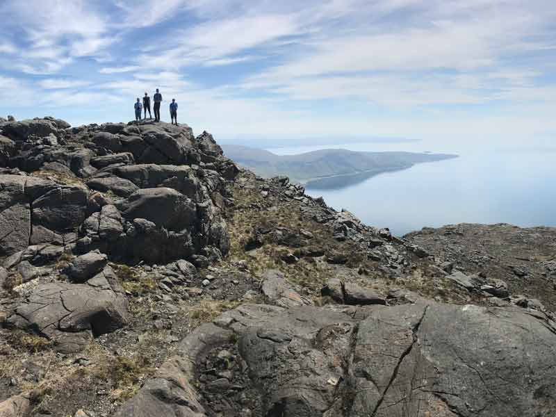 group of people on top of a hill with a sea view on a clear day