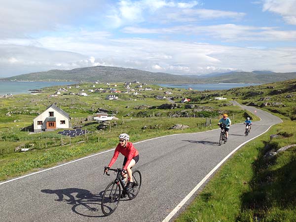 Low carbon travel - A line of cyclists go down the road past fields and houses