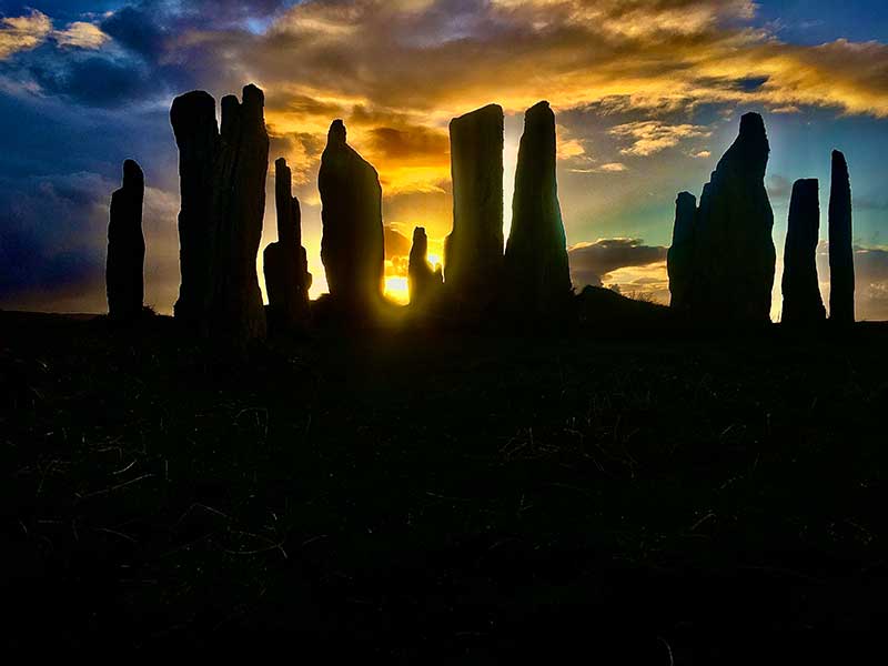 Sunset behind a silhouette of a stone circle