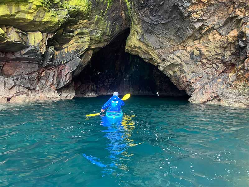 a sea kayaker kayaking into caves