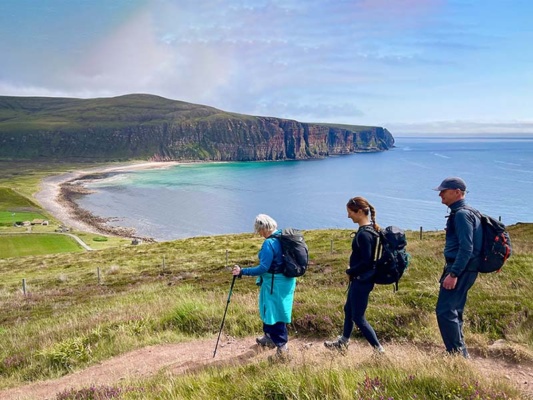 Three hikers walking along a stunning cliff-top vista