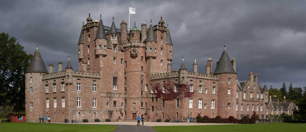 a dramatic towering scottish castle with a dark sky background
