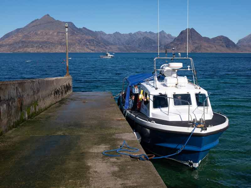a boat in the water, impressive mountain range in the background