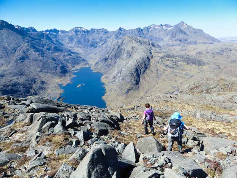 people on a hill above an impressive loch and mountain range