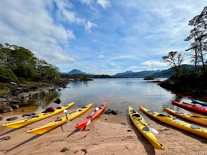 Responsible tourism - Sea kayaks lined up on a beach on Loch Maree